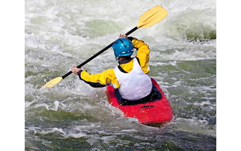 kayaker paddling through rapids