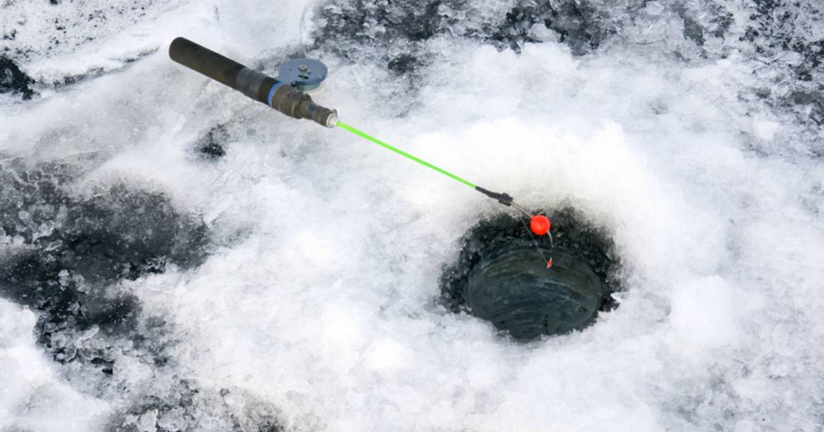 ice fishing hole and a fishing pole laying on the ice