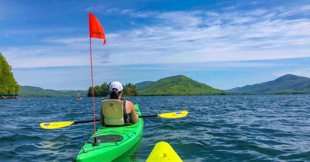 kayakers, one has an orange flag