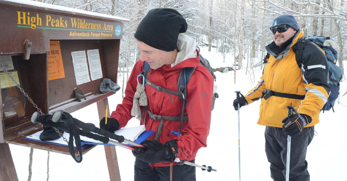 two winter hikers signing in at a trailhead