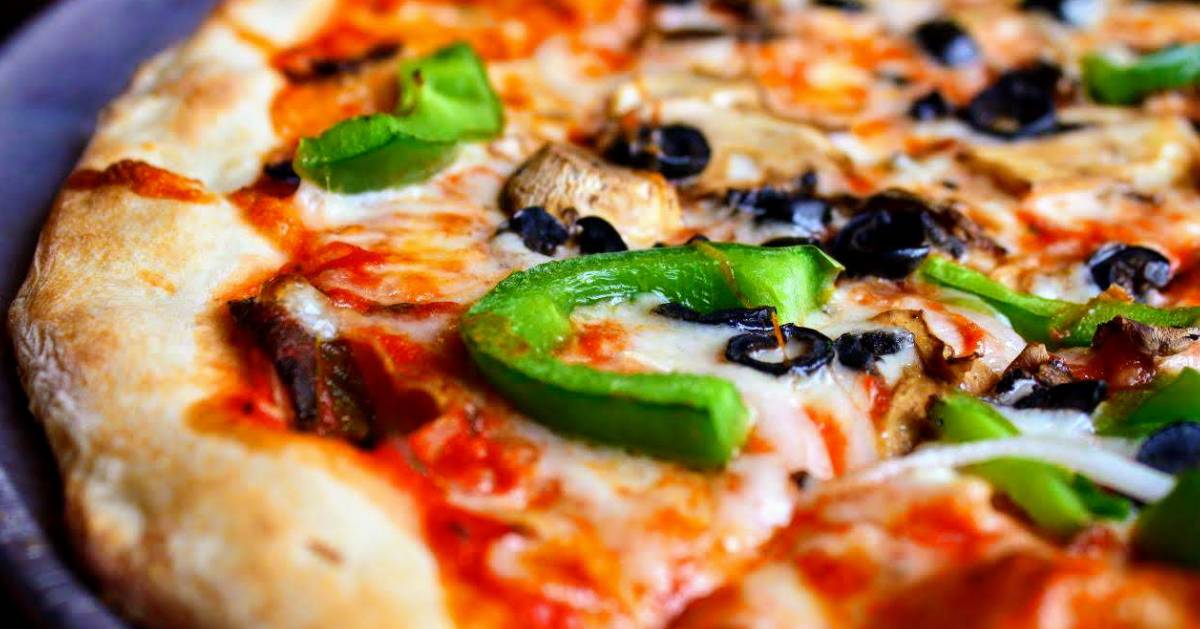 close up of pizza with green peppers, mushrooms, and black olives