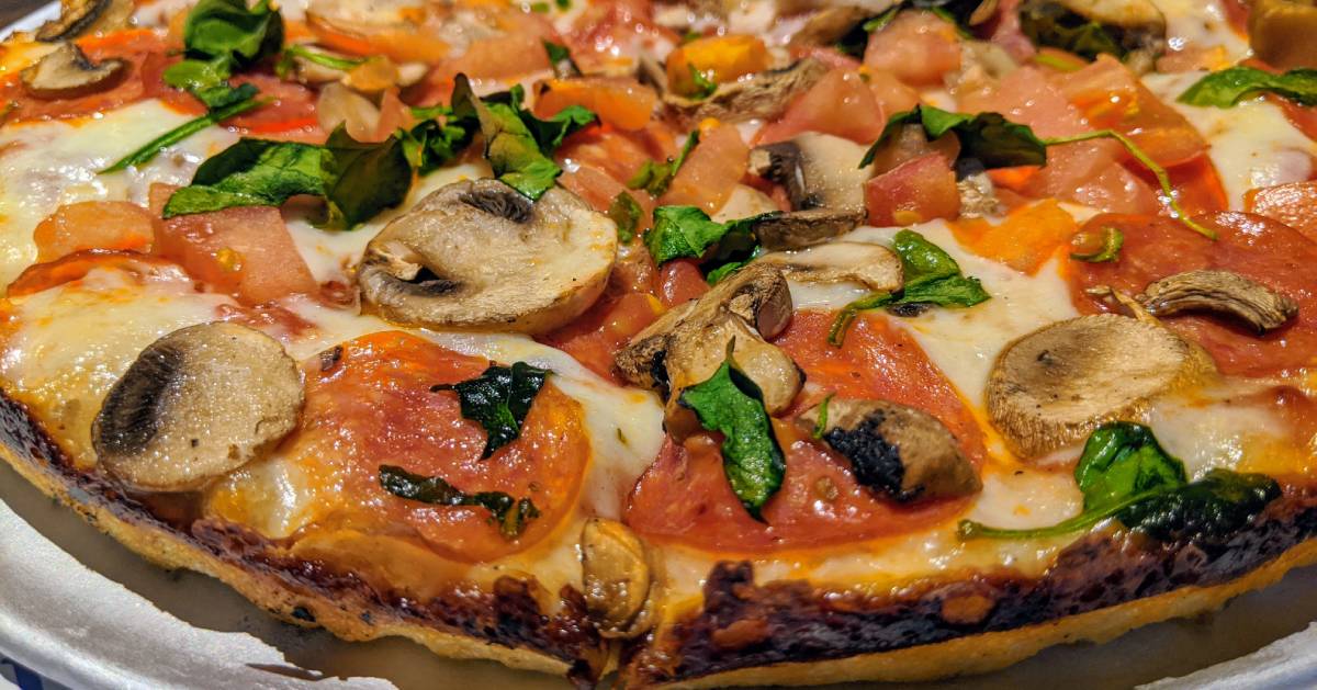 pizza with mushrooms, spinach, tomatoes, and pepperoni