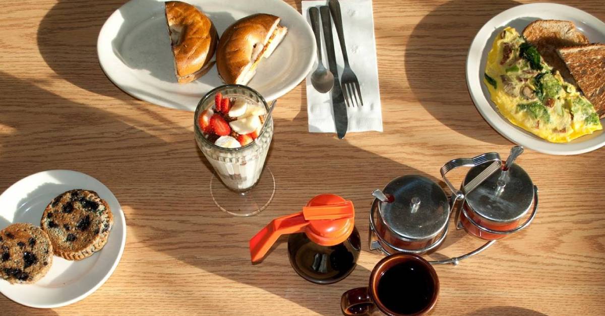 fruit, muffins, a bagel sandwich and other breakfast food on a table