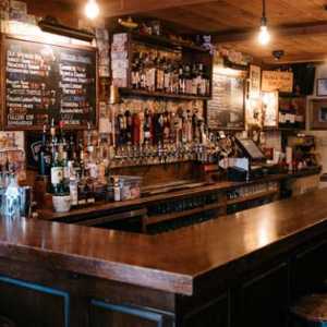 a cozy bar area with a dark wooden bar and stools