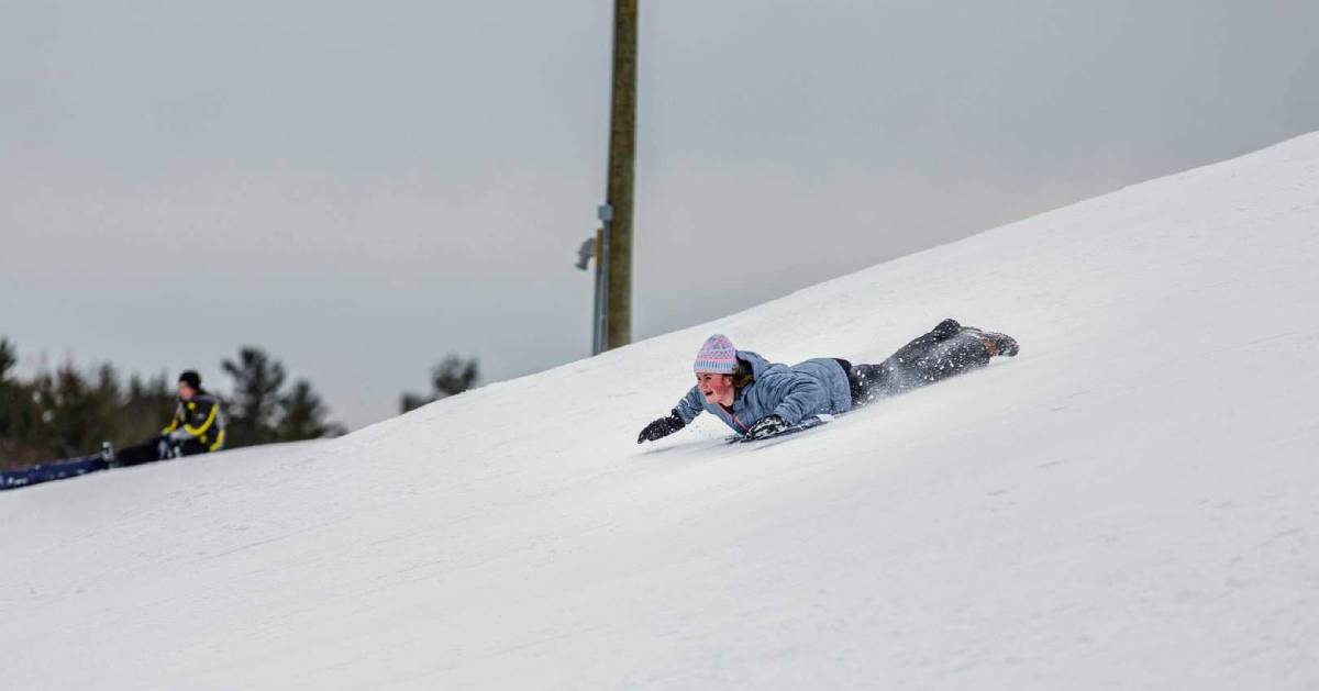 a girl flying down a snowy hill on her stomach