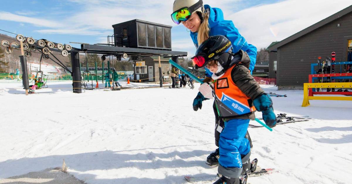 mom helping little boy ski