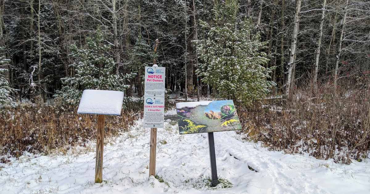 signs along a trail in winter with snow on the ground