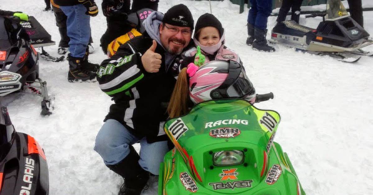 young girl in snowmobile with grandfather