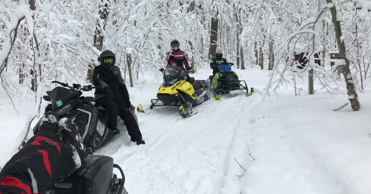 three snowmobilers on a trail