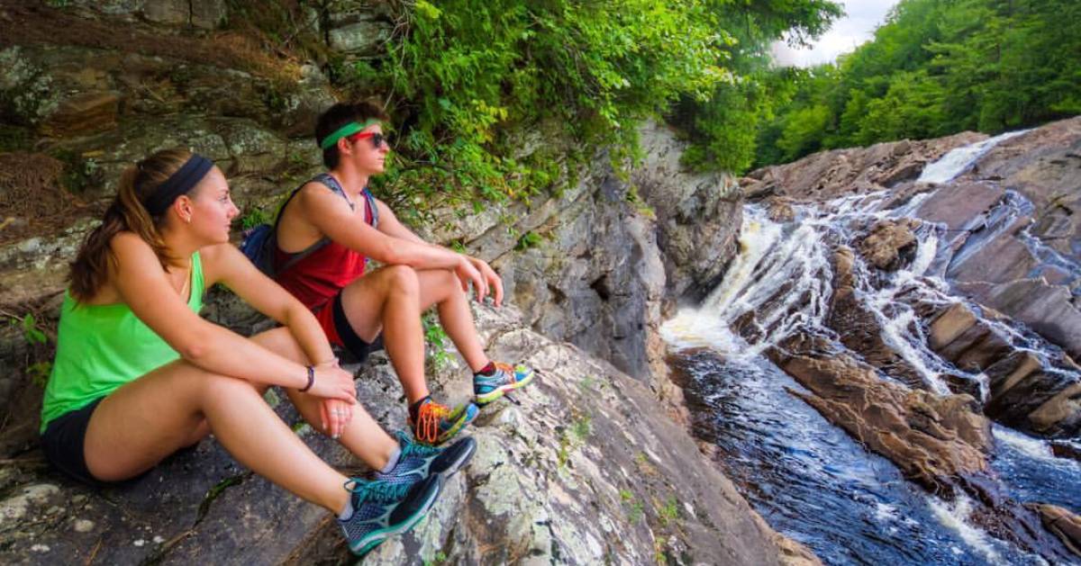 two kids on rocks looking at waterfall