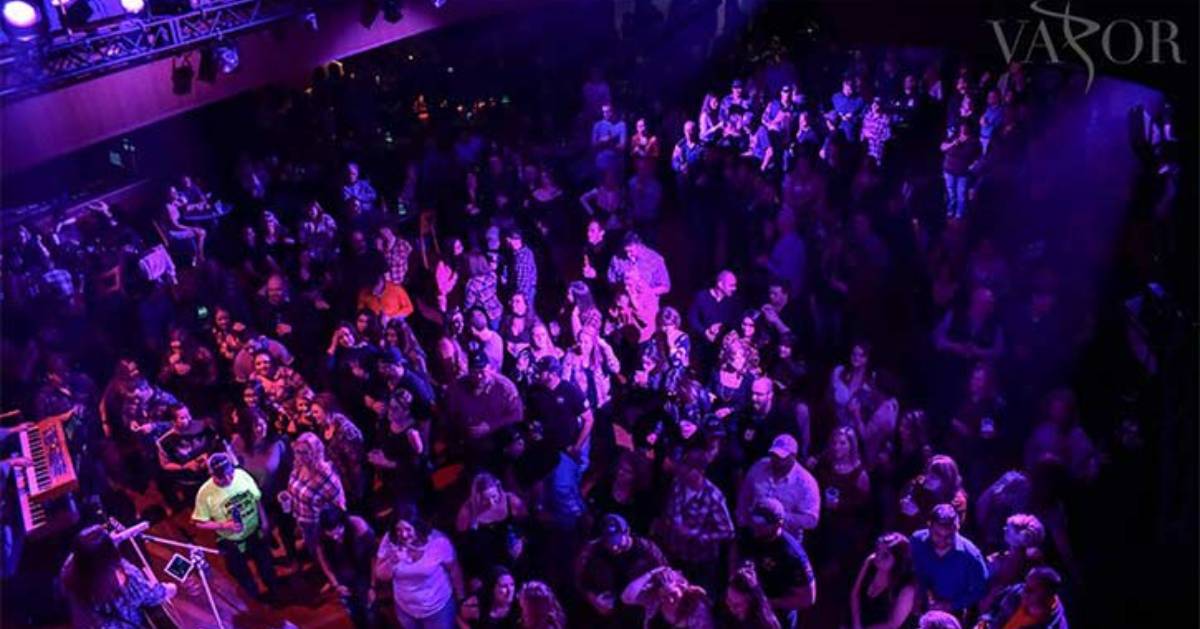 large crowd of people in a nightclub with purple lights shining