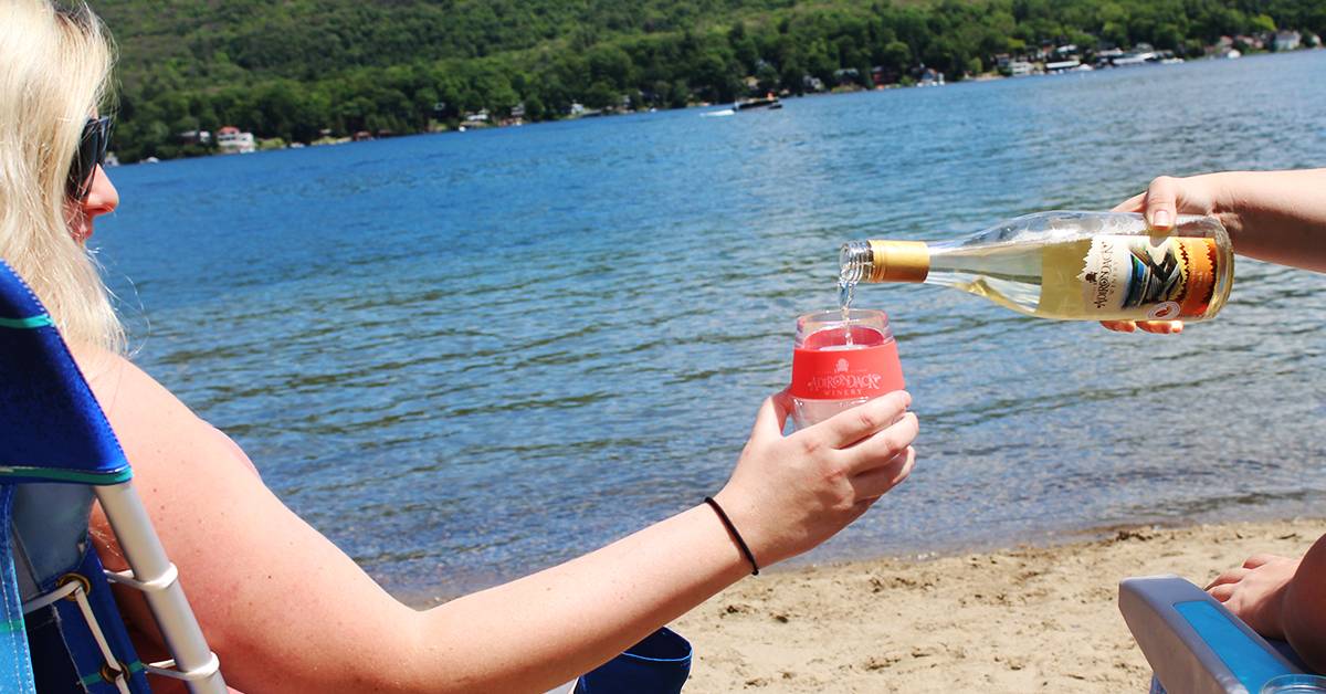 person pouring wine into another person's glass on the beach