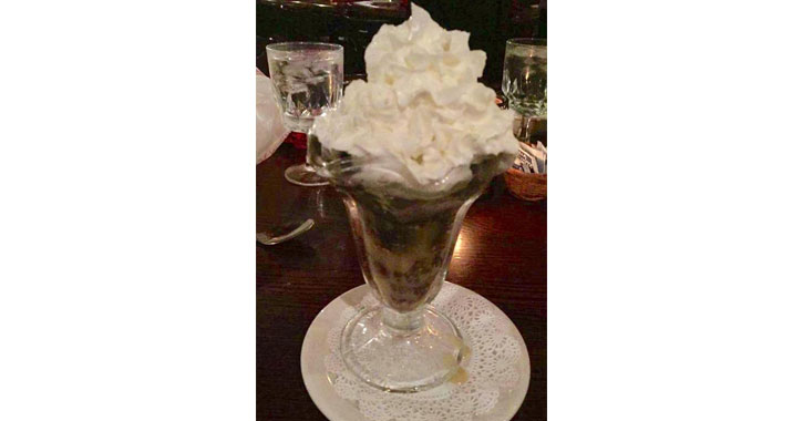 bread pudding served in an ice cream dish with whipped cream