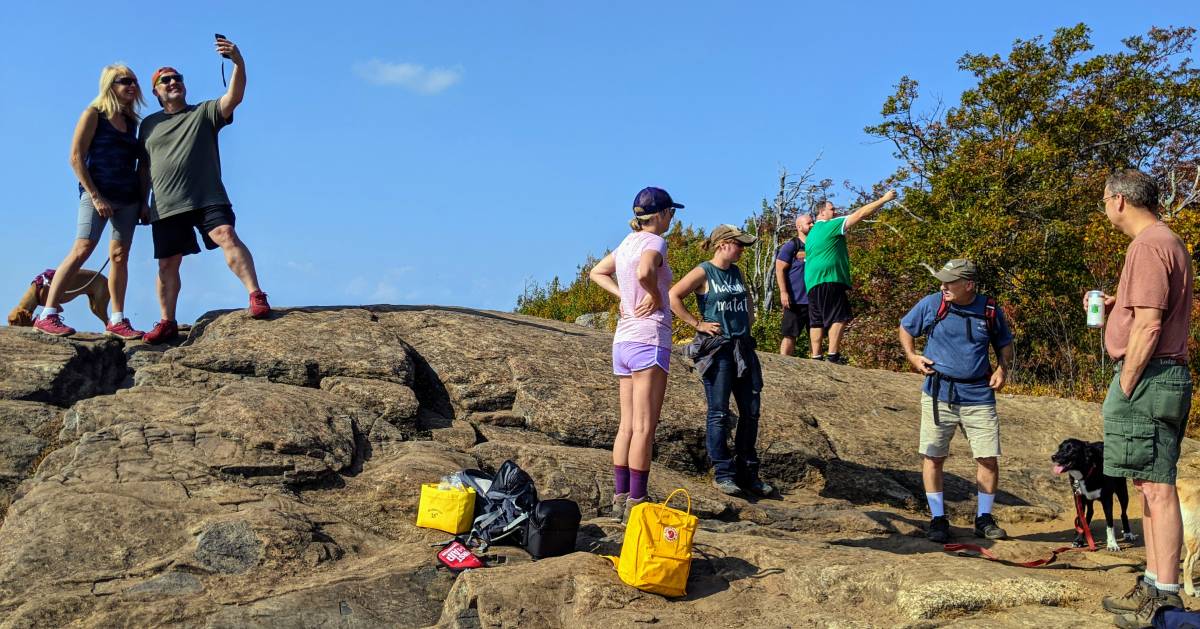 hikers at a summit, some are taking selfies