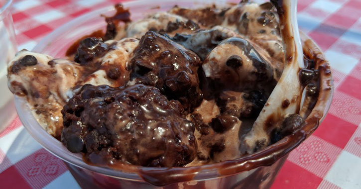 a clear dish on a red checkered tablecloth with a chocolate mixture of ice cream