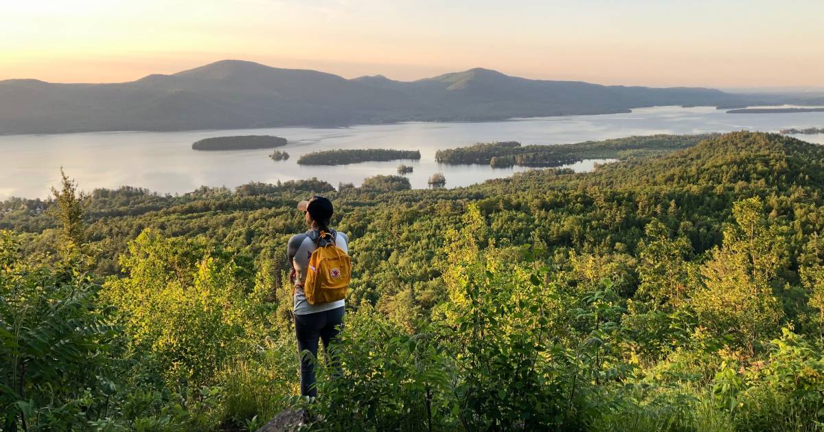hiker girl looks at sunset over lake