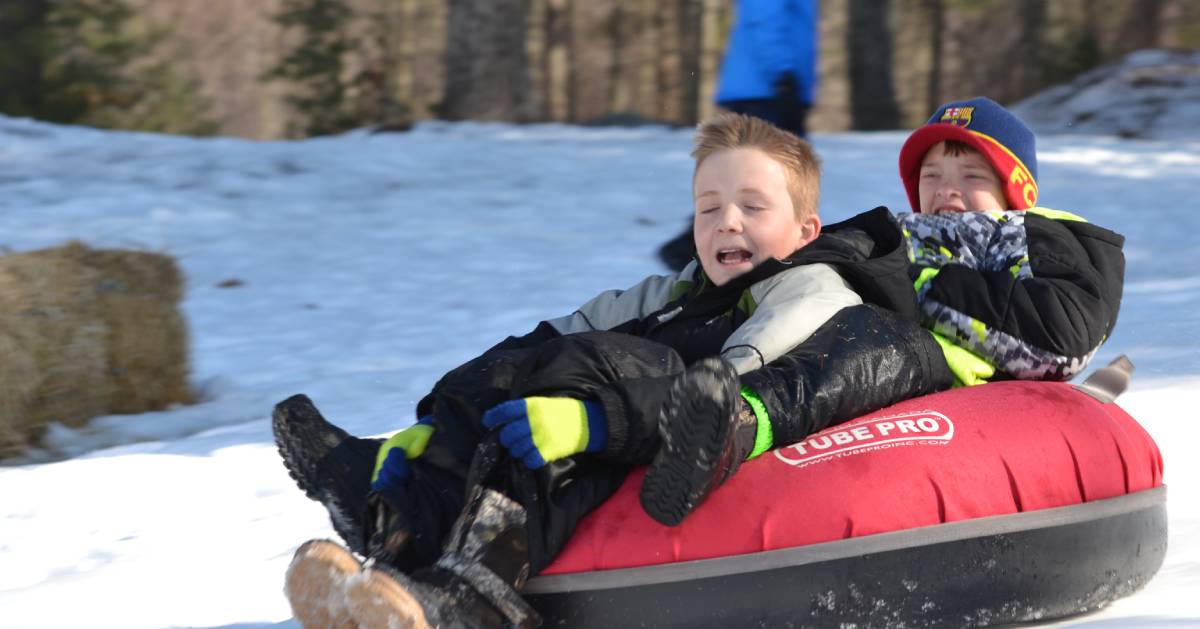 kids riding on a red snow tube