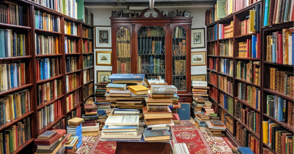 piled books in a bookstore and bookshelves