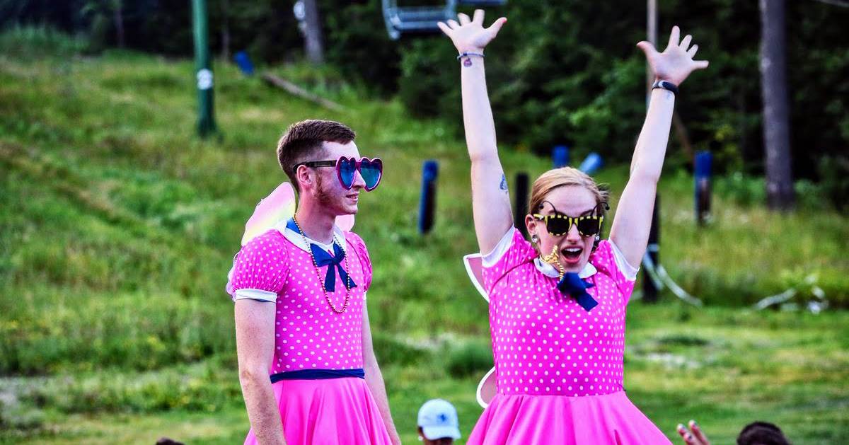 Two Counselors in front of campers wearing pink dresses and sunglasses