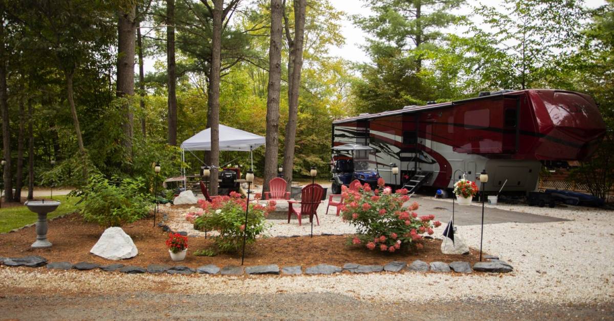 red rv at a campsite with chairs around a fire ring