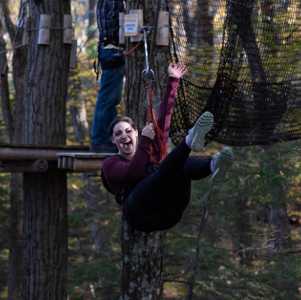 woman ziplines through the woods