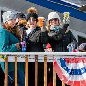 three women standing by people on a restaurant deck in winter