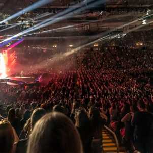 a huge group of people at an indoor concert with bright lights