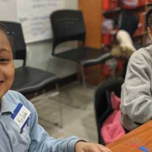 two girls at a school desk smiling