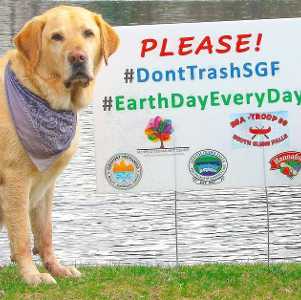 two dogs stand by water and sign about not trashing south glens falls for earth day