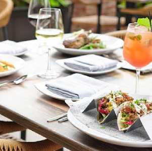 table with cocktails, wine and plates on it outdoors