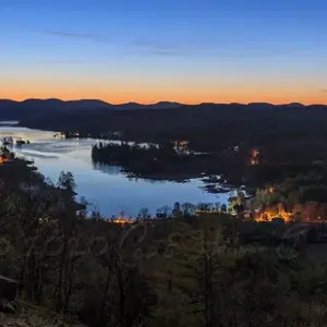 Sunset over Brant Lake, with trees reflecting on calm waters.