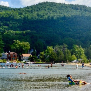 beachgoers in the water and on the beach with mountain in background