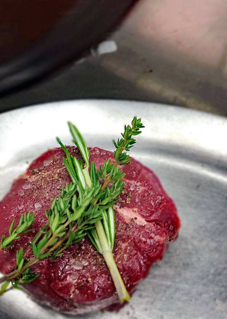 meat with rosemary and thyme sprigs