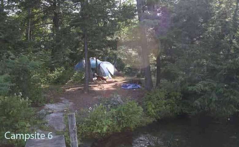 a tent set up just a short distance from a dock and shoreline