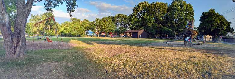 panoramic of park with two playgrounds and bathroom facilities