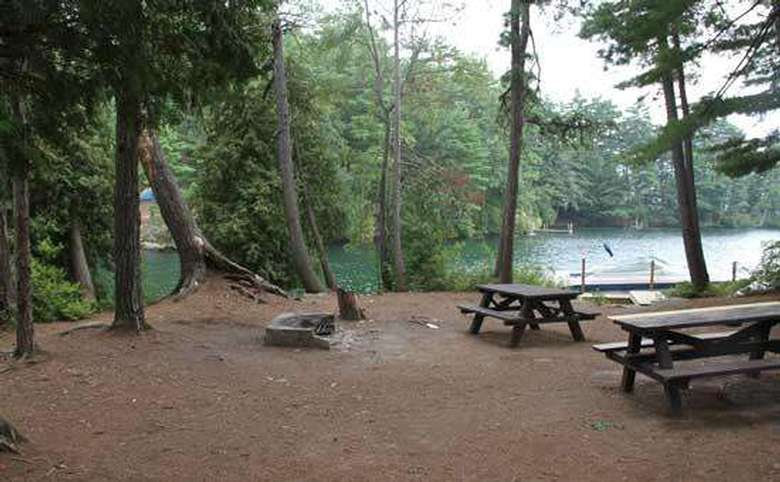a large campsite with two picnic tables and a fire pit in the middle