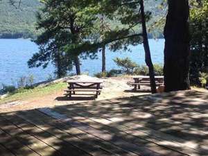 an island campsite with a couple picnic tables and a wooden spot for the tent