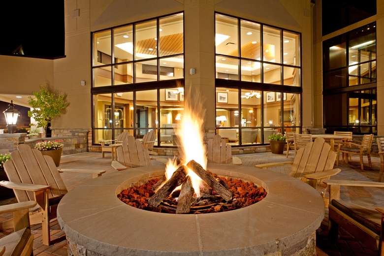 a fire pit surrounded by rustic chairs near a hotel