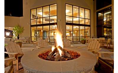 a fire pit surrounded by rustic chairs near a hotel