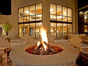 a fire pit surrounded by rustic chairs near a hotel