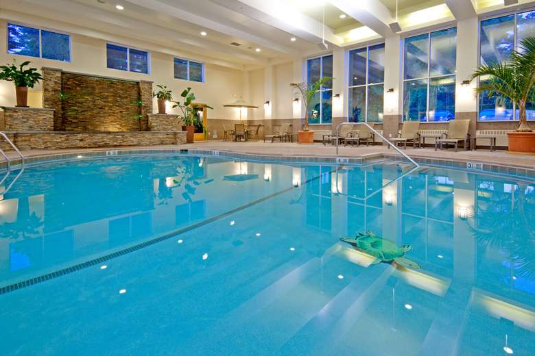 a large blue indoor pool with windows around it