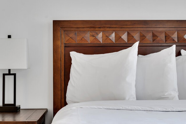 pillows on a large bed near a nightstand and lamp