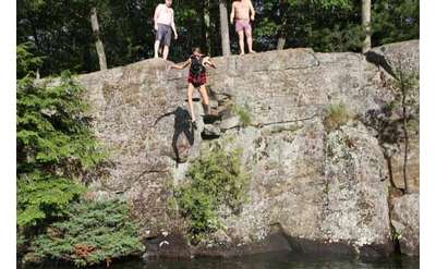 people jumping from cliff into water