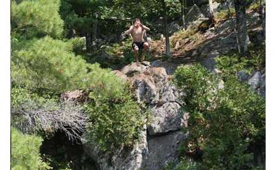 Boy jumping off a cliff into the lake