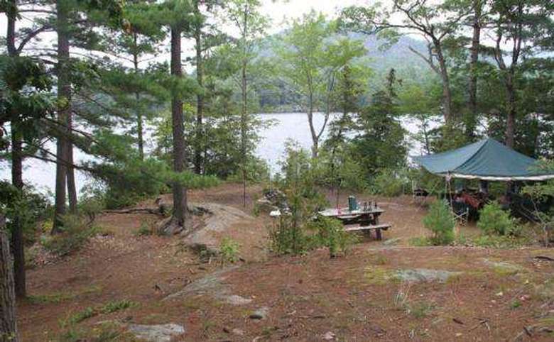 an open tent set up next to a picnic table on an island on a lake