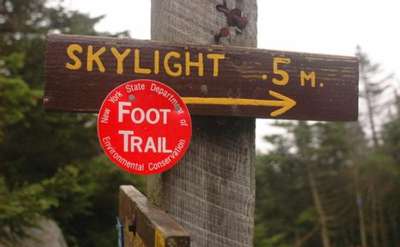 wooden sign that says skylight 0.5m with a red circular trail marker nailed to it