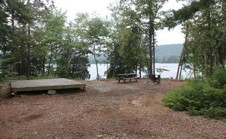 a tent platform and picnic table near the lakeside