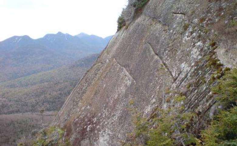 steep rock slide with other mountains visible in the distance