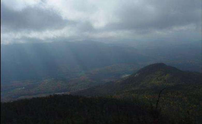 sun shining through thick clouds as seen from a mountain summit