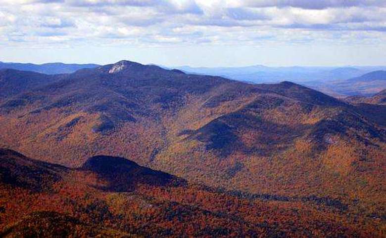view from a mountain summit of surrounding mountains covered in fall foliage